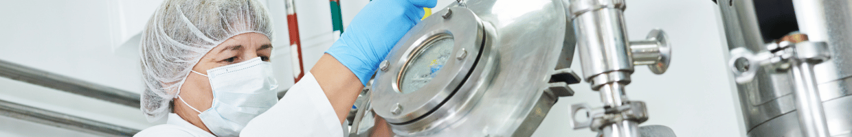 A close-up shot of a woman wearing PPE opening a mixing tank.